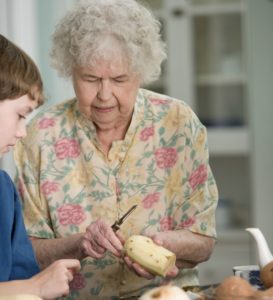 Grandma peeling a potato with grandson watching