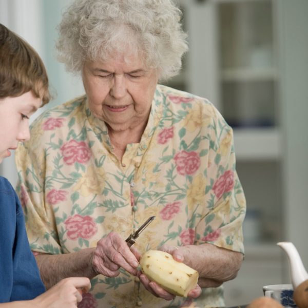 Grandma peeling a potato with grandson watching