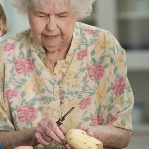 Grandma peeling a potato with grandson watching