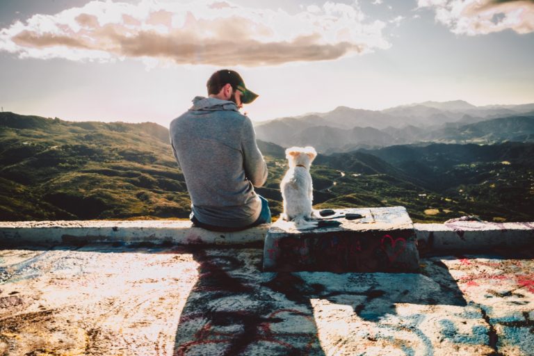 Man sitting with his dog looking at the mountains