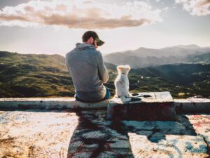 Man sitting with his dog looking at the mountains