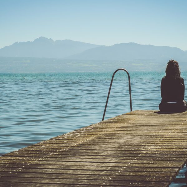 Woman sitting at the end of a dock looking off into the distance