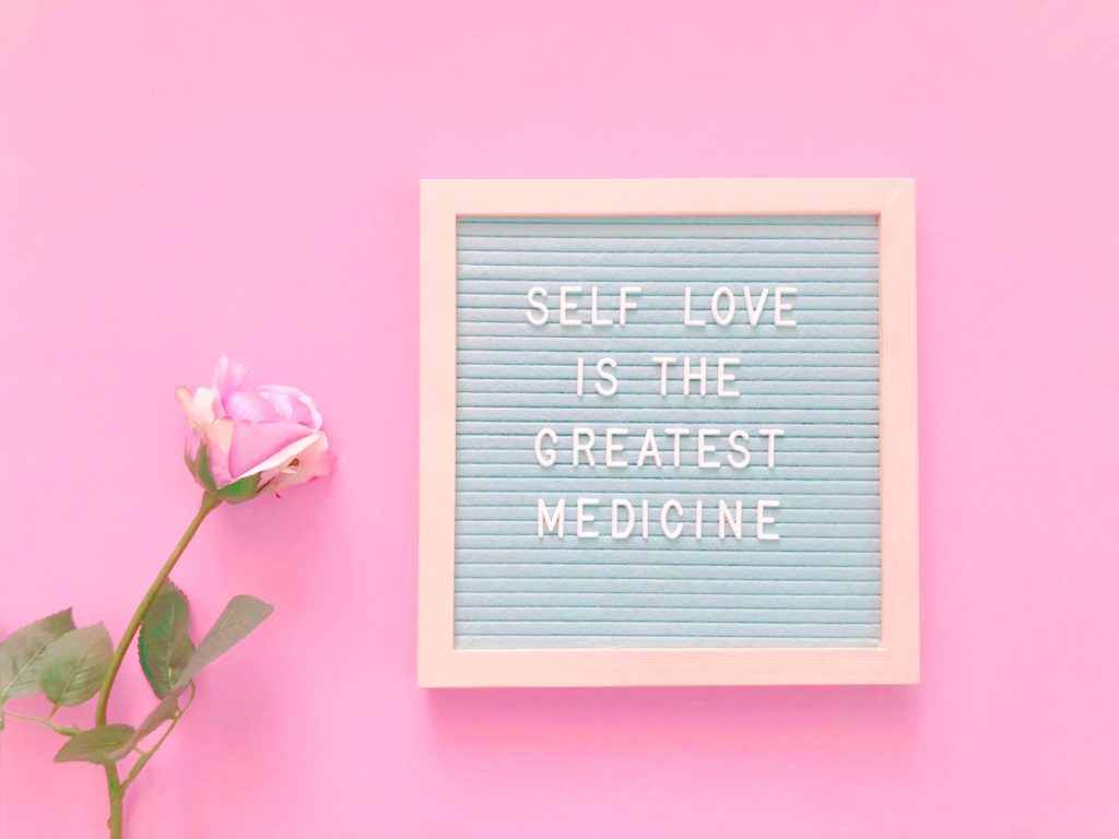 Self Love Message on a board accompanied by a pink rose